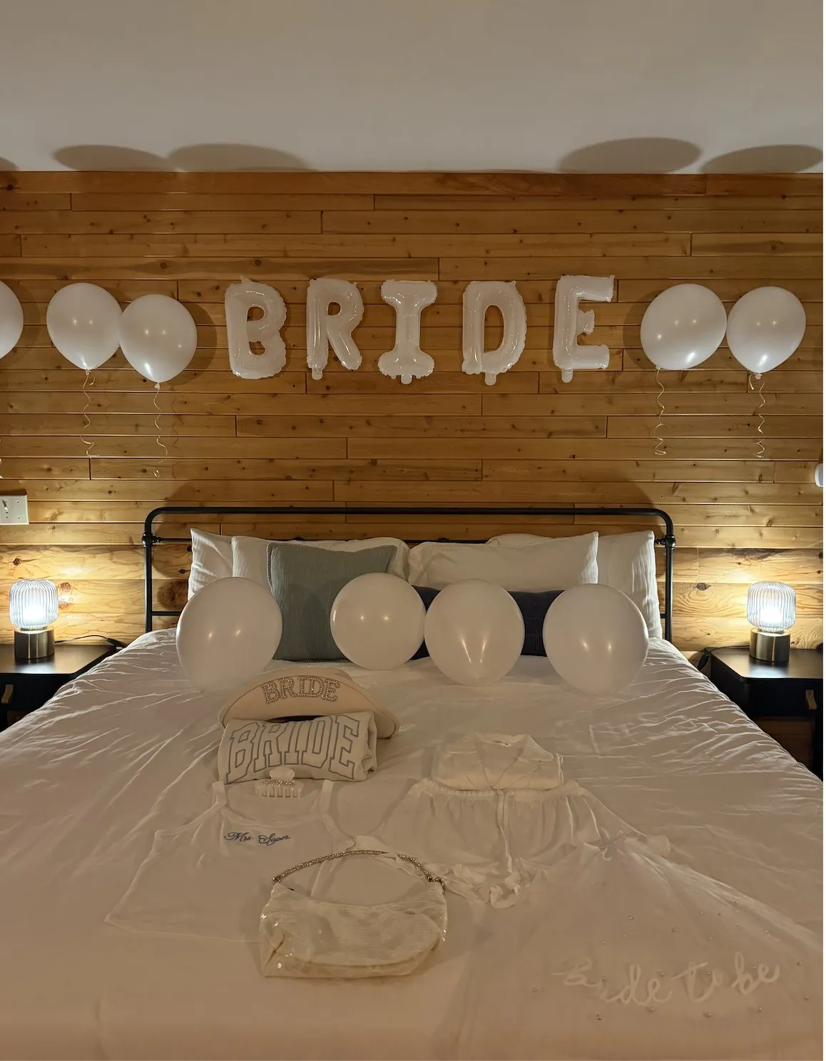 The bride's room set up with white balloons and a BRIDE balloon banner above the bed