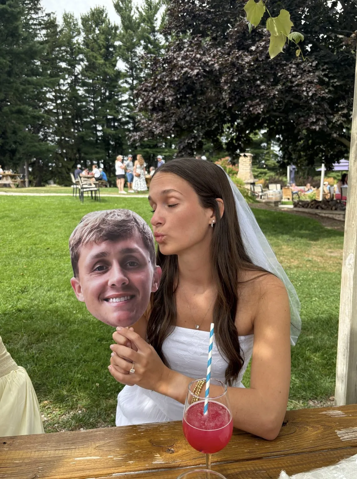The bride holding a cutout of the groom’s face at a winery